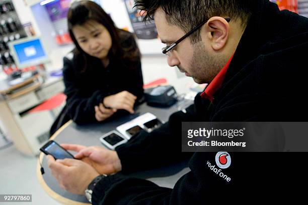 Vodafone employee demonstrates a mobile phone to a customer at a company store in London, U.K., on Wednesday, Nov. 4, 2009. U.K. Prosecutors are...