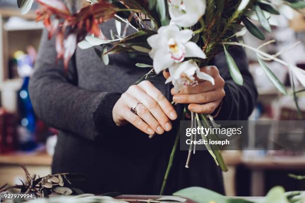 modern florist working with flowers in workshop - with detail on hands - floral decoration stock pictures, royalty-free photos & images
