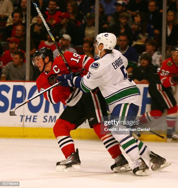 Christian Ehrhoff of the Vancouver Canucks pushes Jonathan Toews of the Chicago Blackhawks at the United Center on October 14, 2009 in Chicago,...