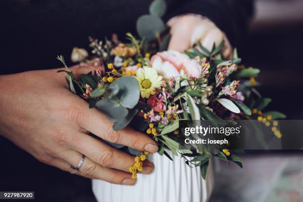 moderne bloemist met bloemen in werkplaats - met detail bezig met handen - bouquet stockfoto's en -beelden