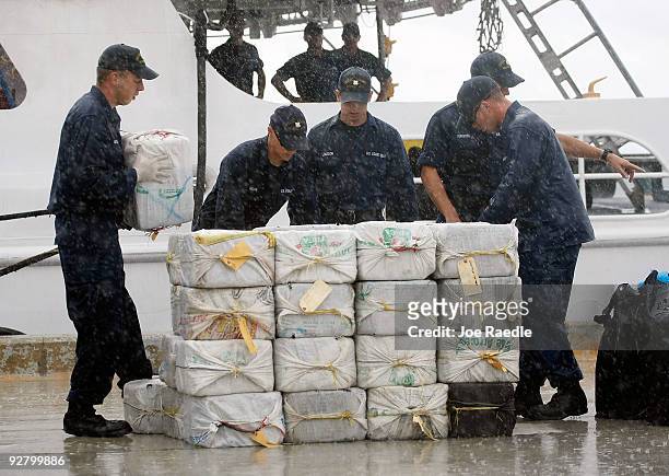 Coast Guard crew members off load bags of cocaine, in a downpour, from Coast Guard Cutter Valiant after it stopped nearly five tons of the drug from...