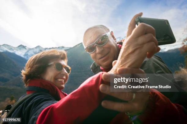 senior couple taking a selfie on a mountain while trekking - excursionismo imagens e fotografias de stock