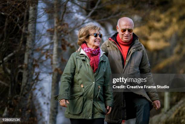 senior couple walking with a spectacular waterfall on the background. - occitanie stock-fotos und bilder