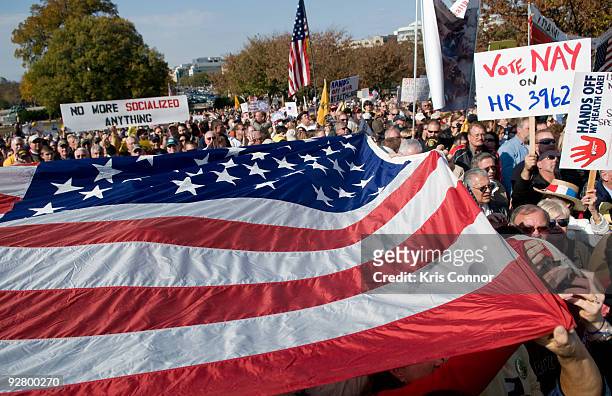 Protestors pass around a giant American flag during a news conference "To Make a Healthcare 'House Call' on Washington" at the US Capitol on November...