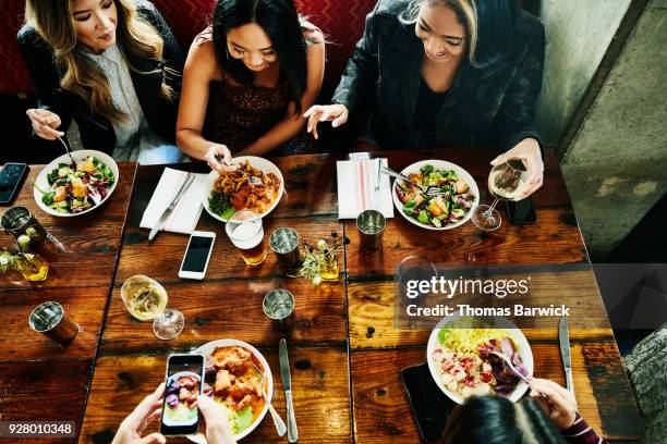 overhead view of smiling female friends sharing lunch in restaurant - taking america to lunch stockfoto's en -beelden