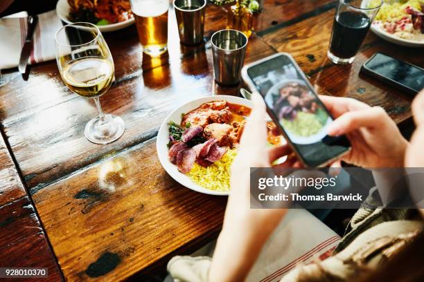 woman taking photo of food with smartphone while having lunch with friends in restaurant - southwest food stock pictures, royalty-free photos & images