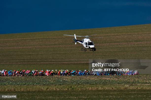 Helicopter hovers as teh pack rides through countryside farmed land during the third stage of the Paris - Nice cycling race between Bourges and...