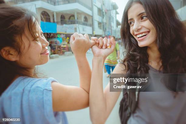 female friends hooking pinky promise with little fingers. - pinky promise stock pictures, royalty-free photos & images