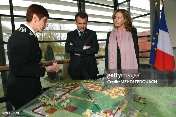 French president Emmanuel Macron flanked by prison guard school director Sophie Bleuet and French Justice Minister Nicole Belloubet look at a scale...