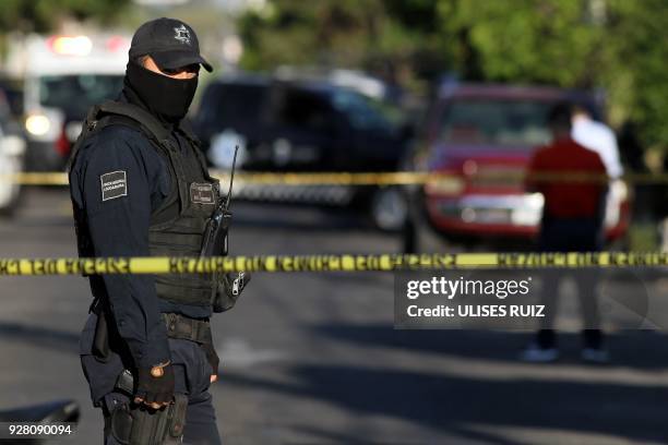 Police officer stands guard as state prosecutors inspect a pick-up truck found abandoned with the bodies of six men, some of them decapitated, which...