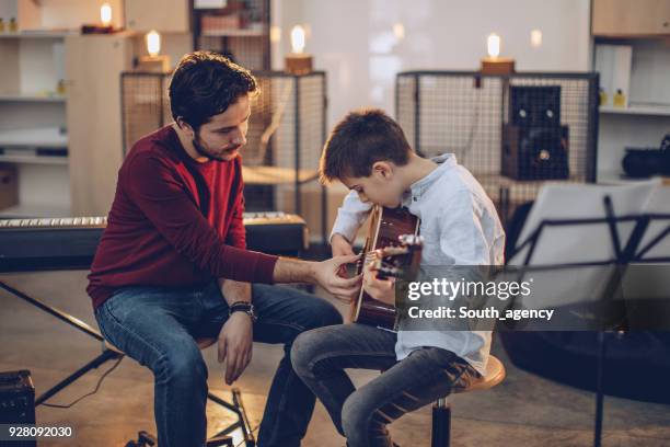 jongen onderwijs om te spelen gitaar in muziekschool - music stockfoto's en -beelden