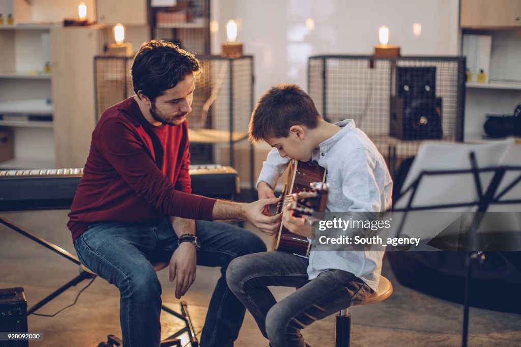 Rapaz ensinando a tocar guitarra na escola de música