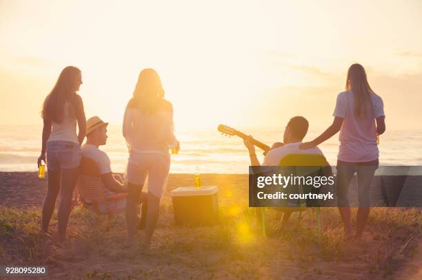 relaxed friends beach party at sunset with 5 people. - beach music stock pictures, royalty-free photos & images