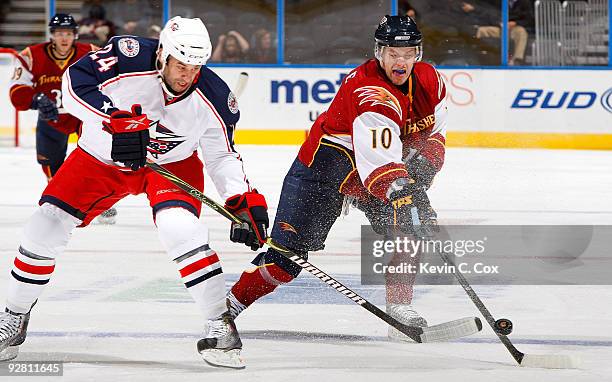 Bryan Little of the Atlanta Thrashers knocks the puck away from Derek MacKenzie of the Columbus Blue Jackets at Philips Arena on November 5, 2009 in...