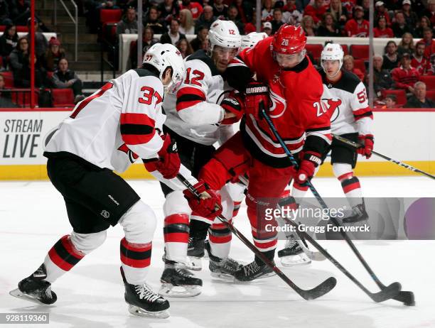 Sebastian Aho of the Carolina Hurricanes attempts to gain control of the puck as he battles with Ben Lovejoy and teammate Pavel Zacha of the New...