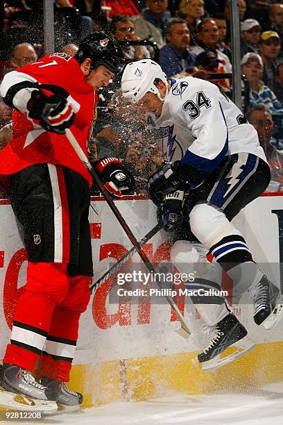 Filip Kuba of the Ottawa Senators and Ryan Craig of the Tampa Bay Lightning crash into the end boards during a game at Scotiabank Place on November...