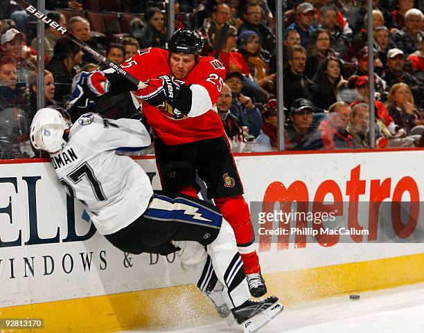 Chris Neil of the Ottawa Senators throws a crushing bodycheck on Victor Hedman of the Tampa Bay Lightning as he skates around the back of the net...