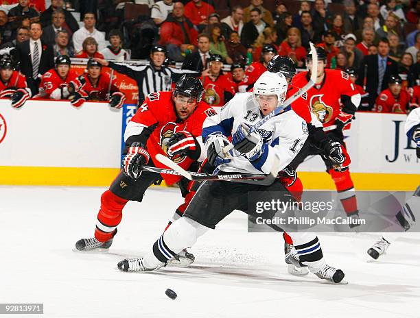 Alex Tanguay of the Tampa Bay Lightning tries to fight through the close checking of Chris Phillips and Chris Kelly of the Ottawa Senators during a...