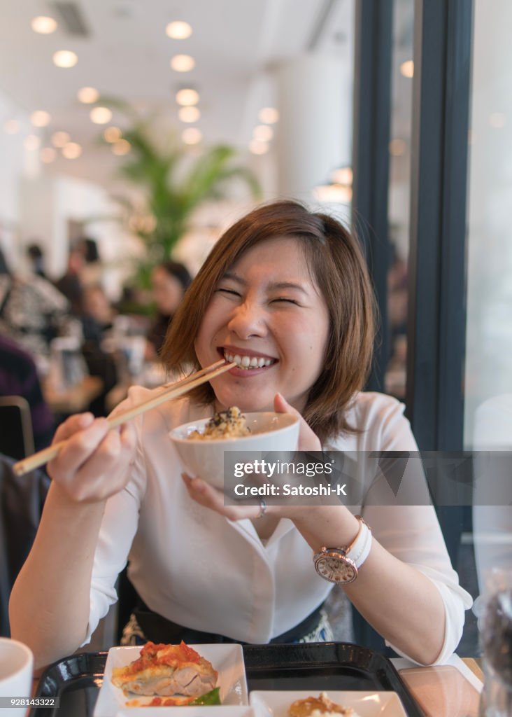 Junge Frau voller Lächeln beim Mittagessen