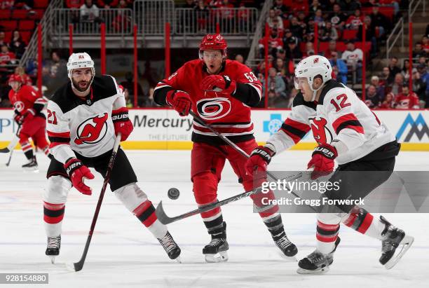 Jeff Skinner of the Carolina Hurricanes reacts to a loose puck as Ben Lovejoy of the New Jersey Devils and teammate Kyle Palmieri looks to gain...