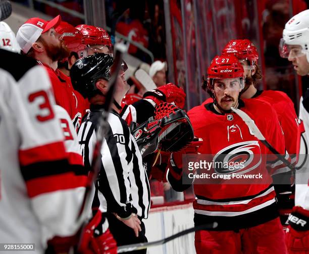 Justin Faulk of the Carolina Hurricanes skates back to the bench to celebrate with teammates in the bench area during an NHL game against the New...
