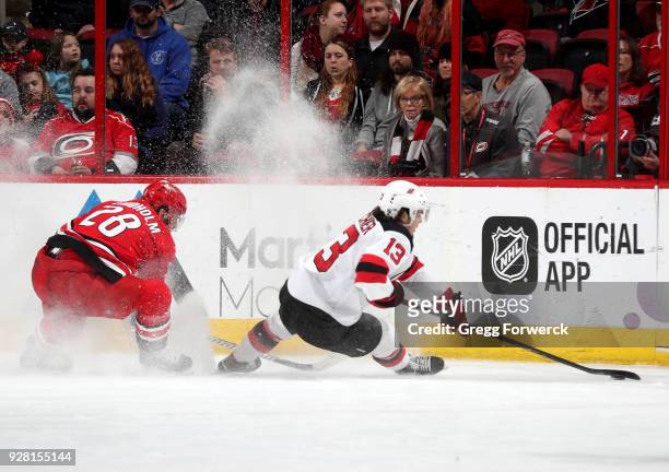 Nico Hischier of the New Jersey Devils controls the puck away from the defense of Elias Lindholm during an NHL game on March 2, 2018 at PNC Arena in...