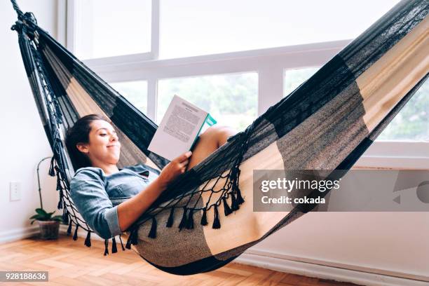 young women reading a book on hammock - hammock stock pictures, royalty-free photos & images