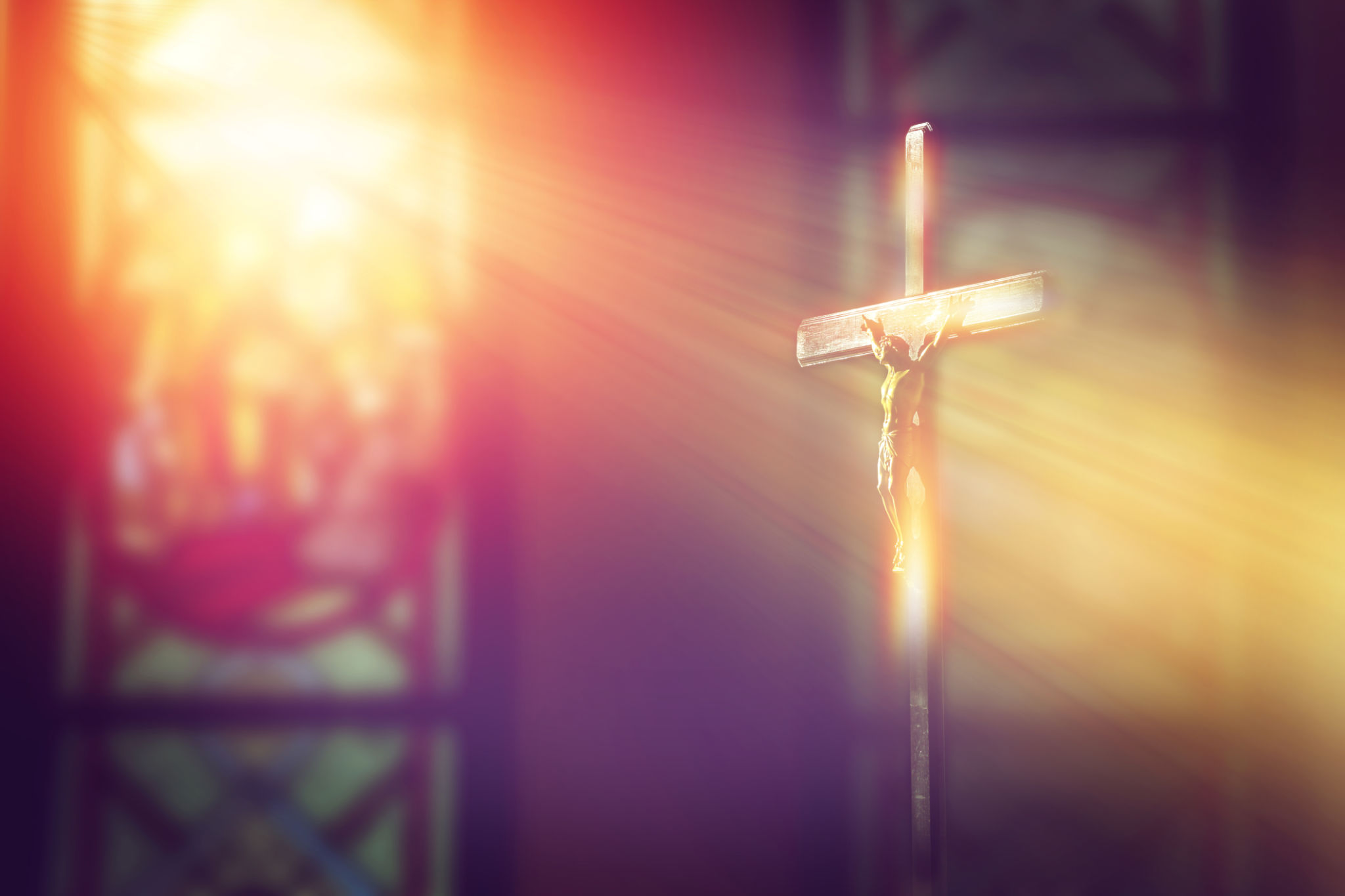 crucifix, jesus on the cross in church with ray of light from stained glass crucifix, jesus on the cross in church with ray of light from stained glass