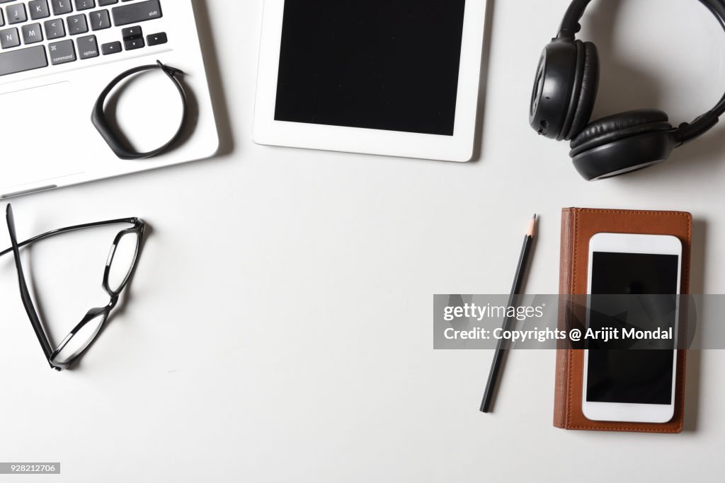 Smartphone on Desk Top View White Background with fitness Tracker, Laptop, Tablet, Smartphone, Bluetooth Headset Copy Space