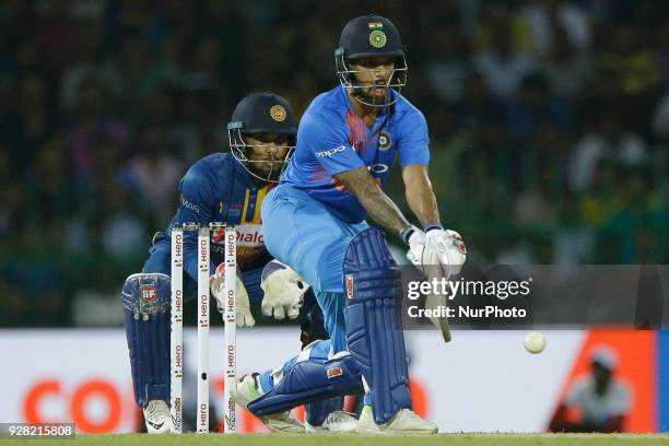 Indian cricketer Shikhar Dhawan plays a reserve sweep shot as Sri Lankan cricketer Dinesh Chandimal looks on during the 1st T20 cricket match of...