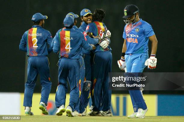 Sri Lankan captain Dinesh Chandimal celebrates with his team mates as Indian cricketer Suresh Raina walks off after his dismissal during the 1st T20...