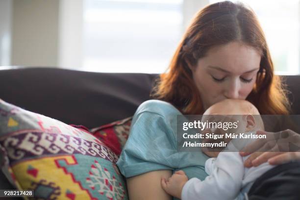 kärleksfull mor kyssar pojke på huvud hemma - mother sleeping baby bildbanksfoton och bilder