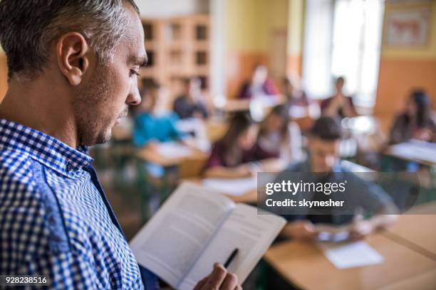 profile view of a professor using a book on a lesson in the classroom. - literature imagens e fotografias de stock