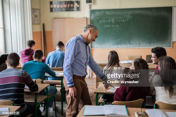 mitte erwachsenen professor hilft seinen schülern während des unterrichts an der high school. - professor stock-fotos und bilder