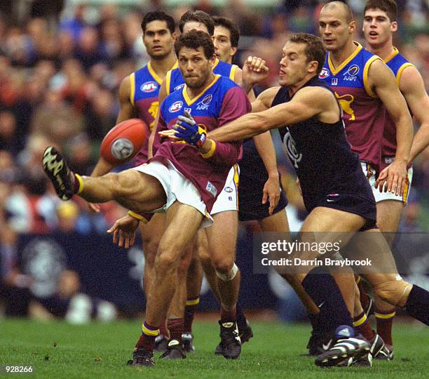 Darryl White of the Brisbane Lions kicks the ball as he is tackled, during the match between the Carlton Blues and the Brisbane Lions, during round...