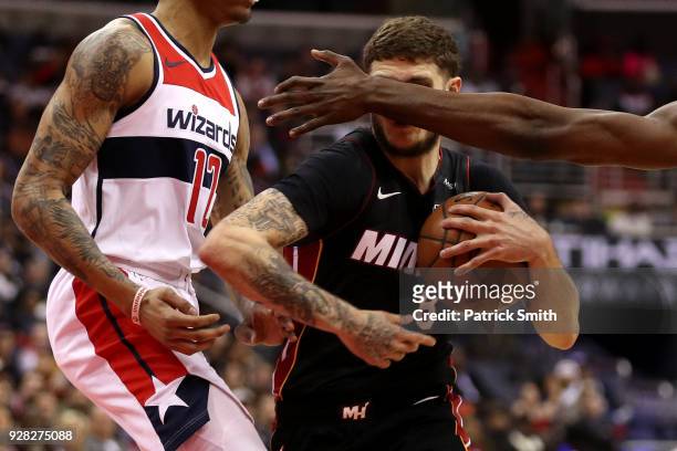 Tyler Johnson of the Miami Heat dribbles past Kelly Oubre Jr. #12 of the Washington Wizards during the first half at Capital One Arena on March 6,...