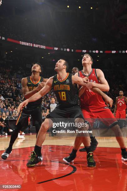 John Collins and Miles Plumlee of the Atlanta Hawks box out Jakob Poeltl of the Toronto Raptors on March 6, 2018 at the Air Canada Centre in Toronto,...