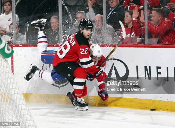 Damon Severson of the New Jersey Devils checks Alex Galchenyuk of the Montreal Canadiens into the board during the third period at the Prudential...