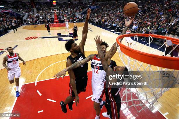 Kelly Oubre Jr. #12 of the Washington Wizards shoots in front of Rodney McGruder of the Miami Heat during the first half at Capital One Arena on...