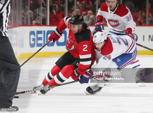 John Moore of the New Jersey Devils and Phillip Danault of the Montreal Canadiens battle for a loose puck during the game at Prudential Center on...