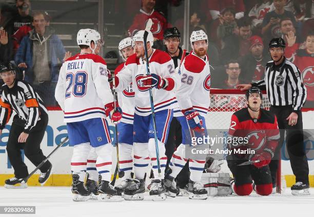 The Montreal Canadiens celebrate a goal by Byron Froese as Ben Lovejoy of the New Jersey Devils looks away duering the game at Prudential Center on...