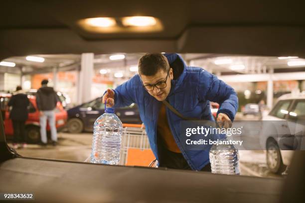 homme d’emballage épicerie supermarché dans le coffre de voiture - carrying photos et images de collection