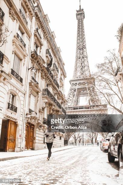 man running to the eiffel tower with snow - eiffel tower christmas stock pictures, royalty-free photos & images