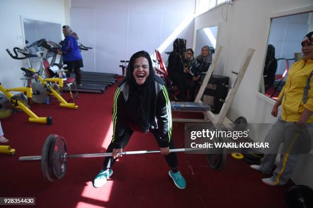 In this Photo taken on March 4 Afghanistan national powerlifting team member Rasheda Parhiz reacts during a deadlift exercise as teammate Sadya Ayubi...