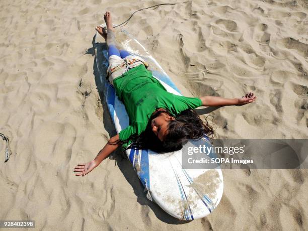 Girl seen taking a rest on her surfing board. Young people in the world´s longest sandy beach in Cox´s Bazar, Bangladesh, decided to throw away...