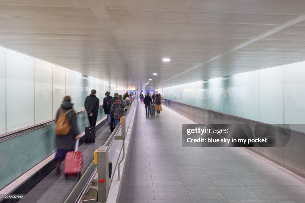 Passengers passing and walking along the conveyor belt at an airport.