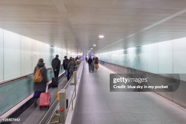 passengers passing and walking along the conveyor belt at an airport. - heathrow airport fotografías e imágenes de stock