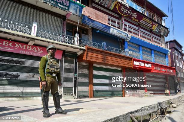 An Indian paramilitary trooper stands guard near the closed shops during restrictions in Srinagar, Indian administered Kashmir. Authorities imposed...