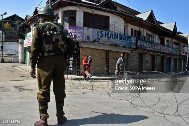 Pedestrians walk past Indian policeman standing guard during restrictions in Srinagar, Indian administered Kashmir. Authorities imposed restrictions...