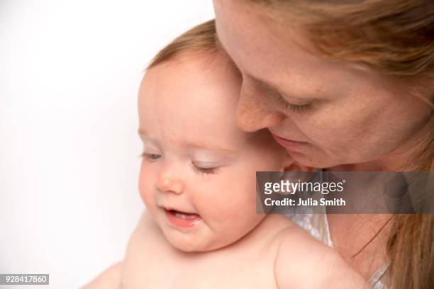 caucasian mother, 31, and caucasian baby, 10 months, on white seamless looking down - julia smith stockfoto's en -beelden